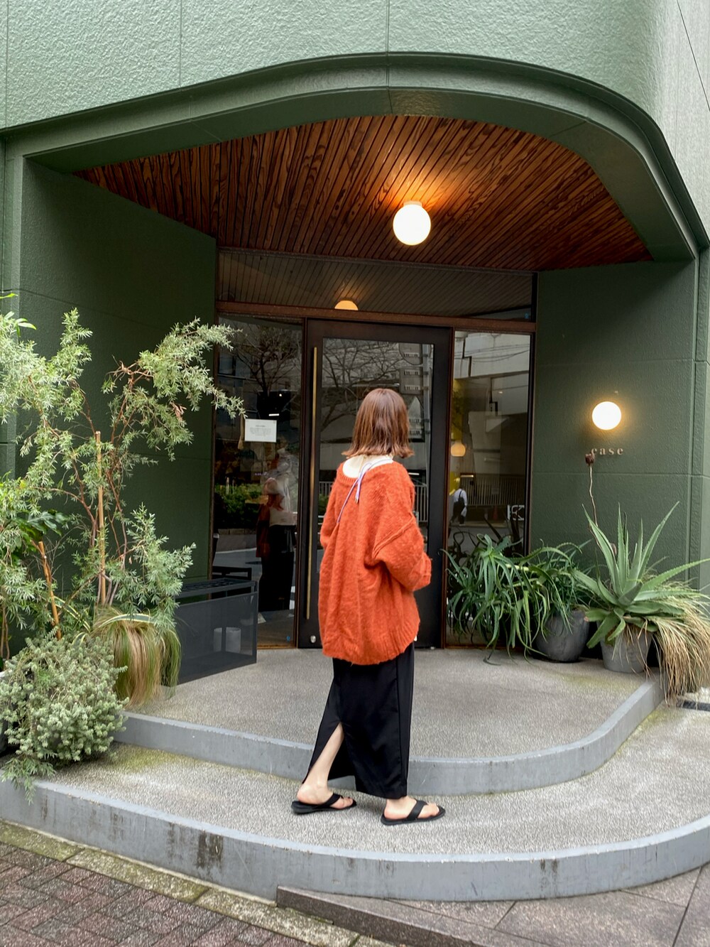 オレンジ系のカーディガン/ボレロ、ブラック系のスカート、ホワイト系のトップスを着用したレディースの春コーディネートの3枚目の写真