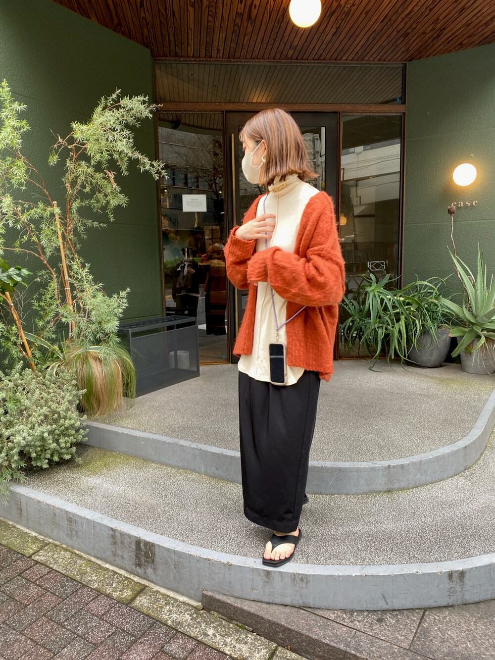 オレンジ系のカーディガン/ボレロ、ブラック系のスカート、ホワイト系のトップスを着用したレディースの春コーディネートの2枚目の写真