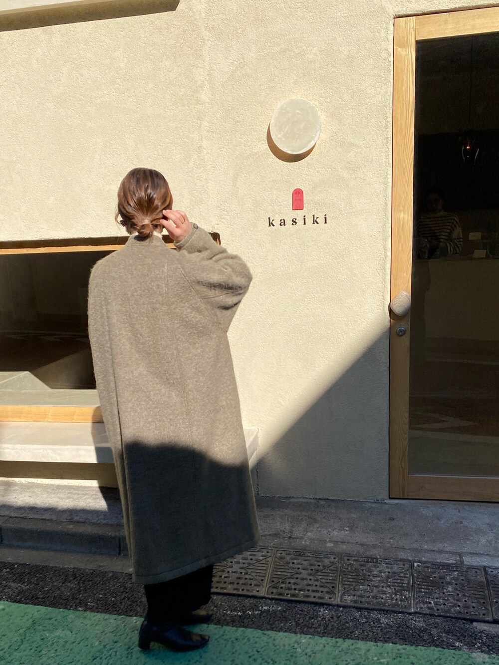 ブラウン系のブーツ、ブラウン系のノーカラーコート、ホワイト系のバッグを着用したレディースの春コーディネートの2枚目の写真