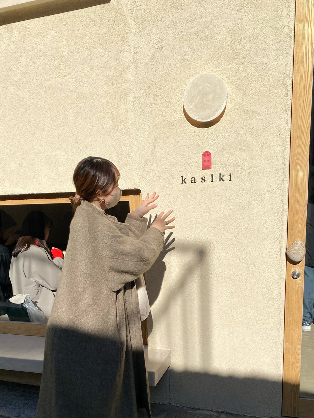 ブラウン系のブーツ、ブラウン系のノーカラーコート、ホワイト系のバッグを着用したレディースの春コーディネートの3枚目の写真