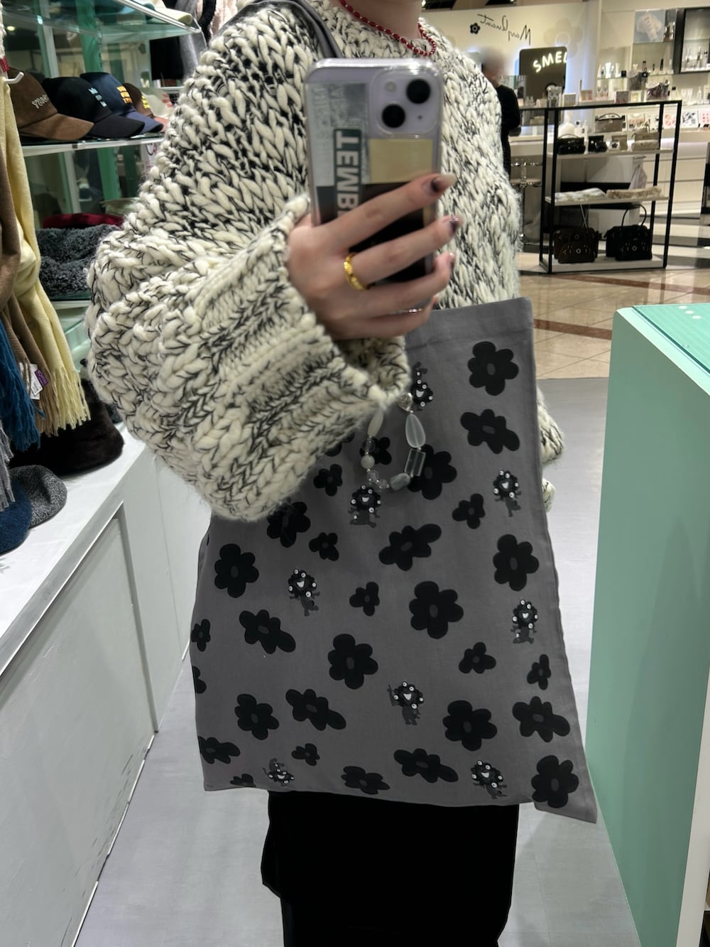 グレー系のトートバッグ、グレー系のキーホルダー、レッド系のネックレスを着用したレディースの冬コーディネートの2枚目の写真