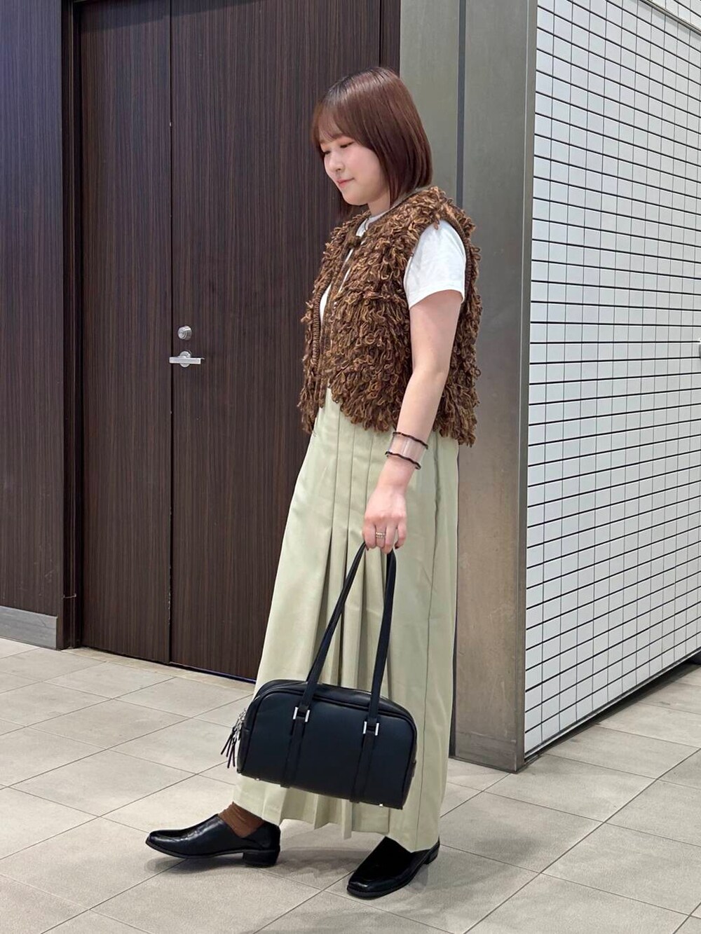 ホワイト系のTシャツ/カットソー、ブラウン系のベスト、ブラック系のボストンバッグを着用したレディースの夏コーディネートの6枚目の写真