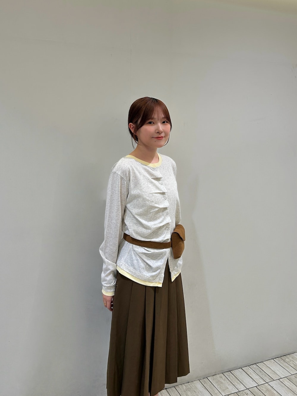 ベージュ系のTシャツ/カットソー、イエロー系のボディバッグ/ウエストポーチ、ブラウン系のスカートを着用したレディースの秋コーディネートの4枚目の写真