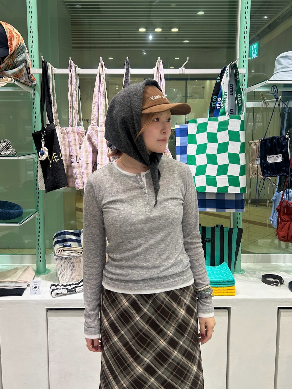 ブラック系のスニーカー、ブラウン系のスカート、ブラック系のショルダーバッグを着用したレディースの秋コーディネートの4枚目の写真