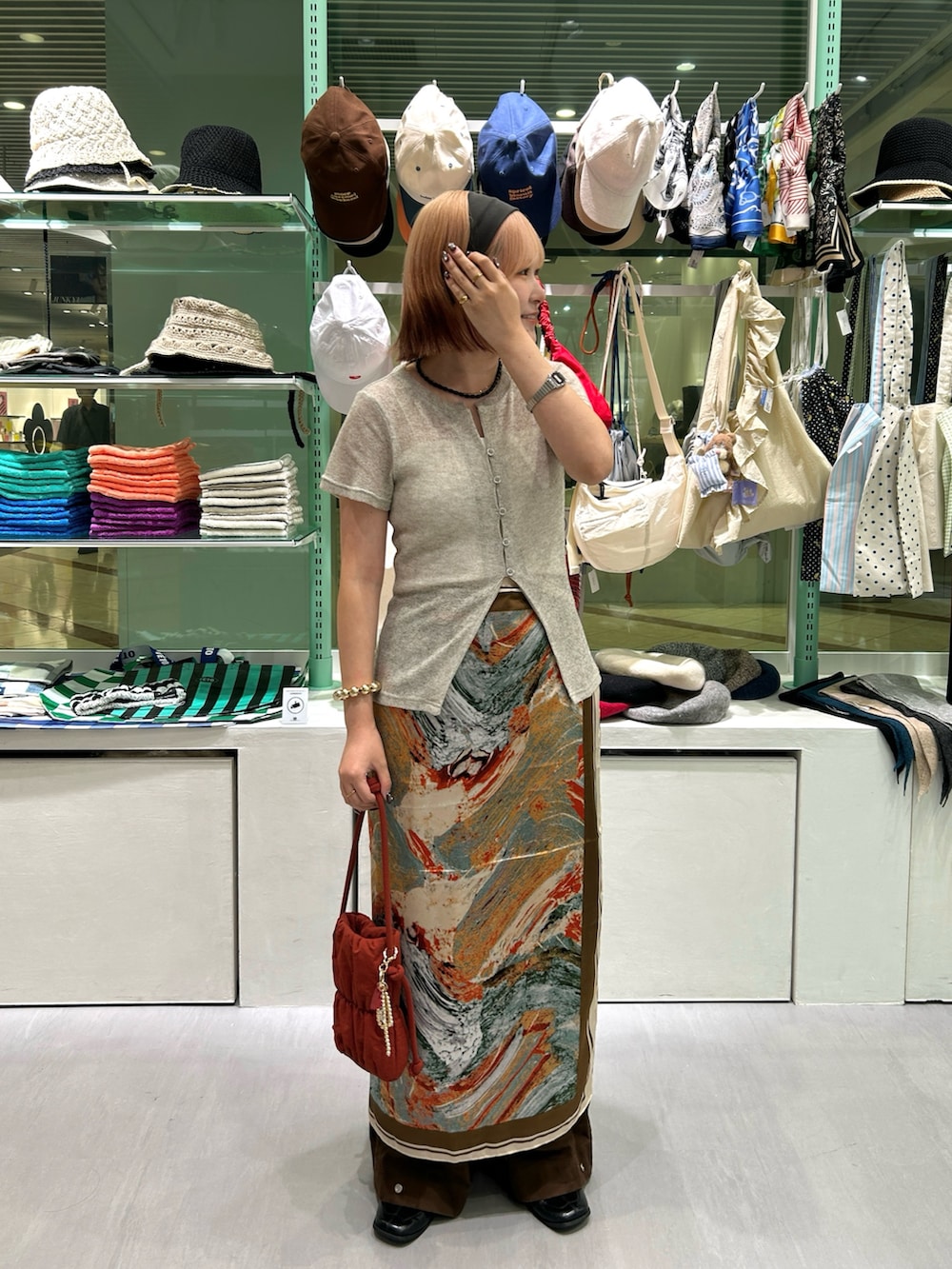 レッド系のショルダーバッグ、ブラック系のネックレス、ゴールド系のネックレスを着用したレディースの秋コーディネートの3枚目の写真