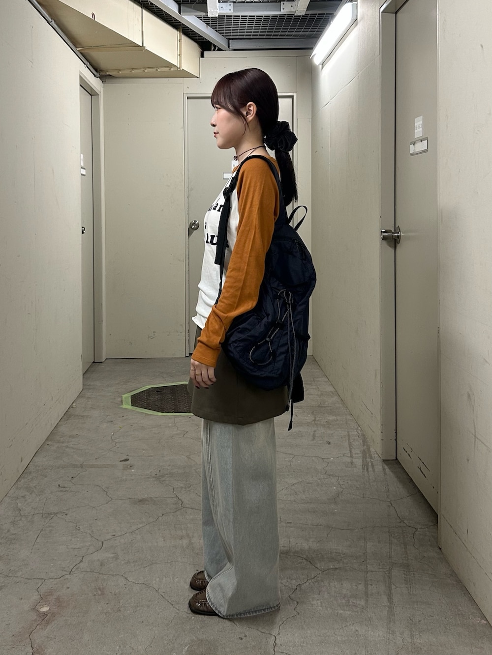 グリーン系のスカート、ブルー系のデニムパンツ、ブラウン系のローファーを着用したレディースの秋コーディネートの3枚目の写真