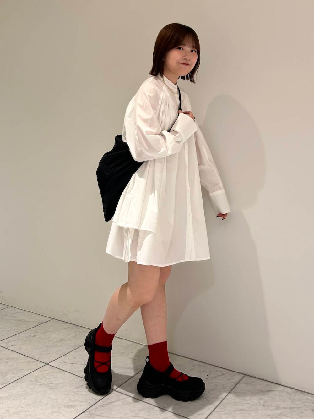 ブラック系のスニーカー、ブラウン系のベスト、ホワイト系のワンピースを着用したレディースの夏コーディネートの5枚目の写真