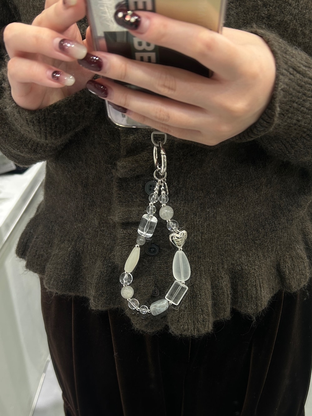 グレー系のトートバッグ、グレー系のキーホルダー、レッド系のネックレスを着用したレディースの冬コーディネートの3枚目の写真