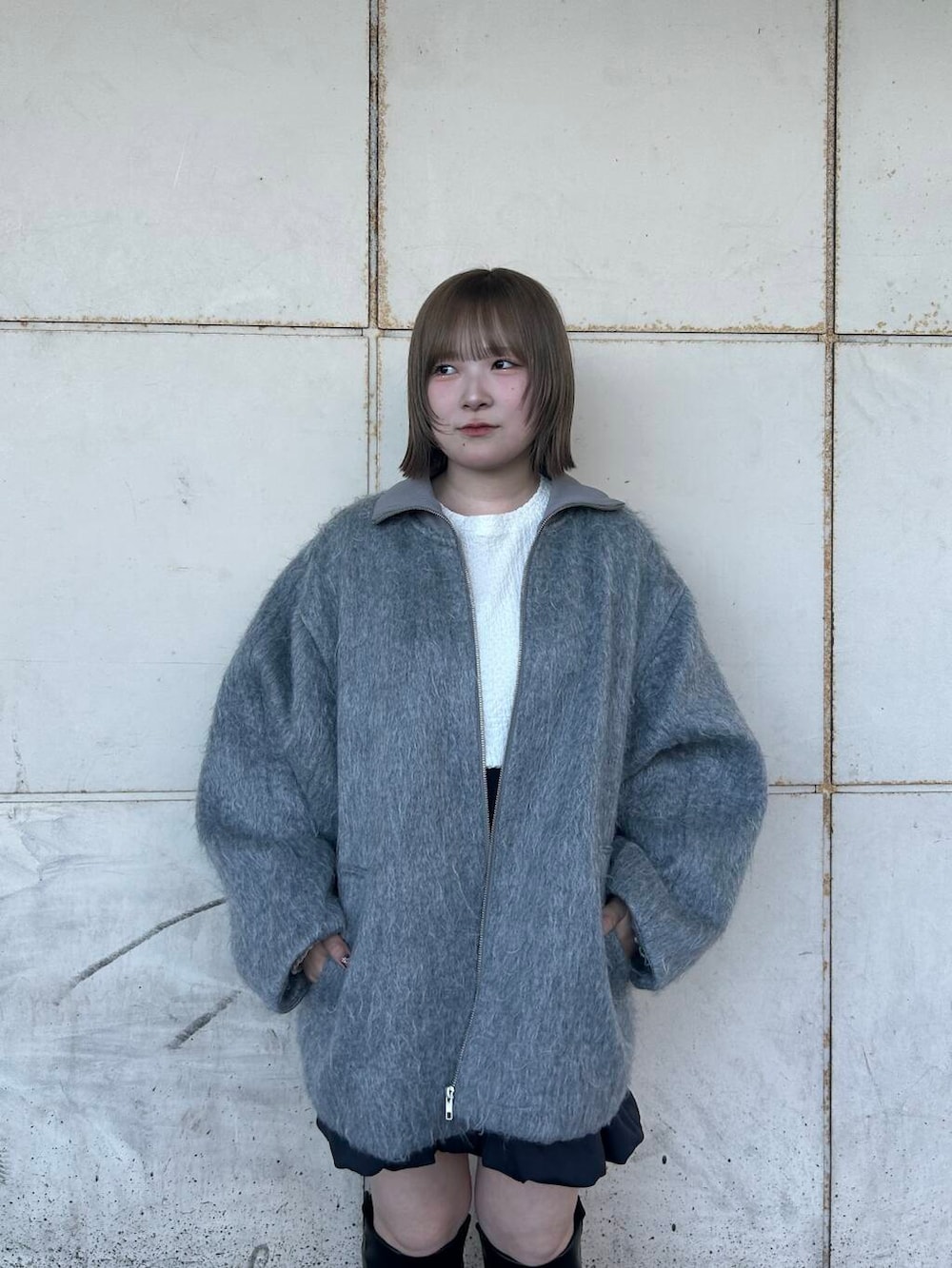 グレー系のスカート、ブラック系のブーツ、ホワイト系のTシャツ/カットソーを着用したレディースの秋コーディネートの4枚目の写真