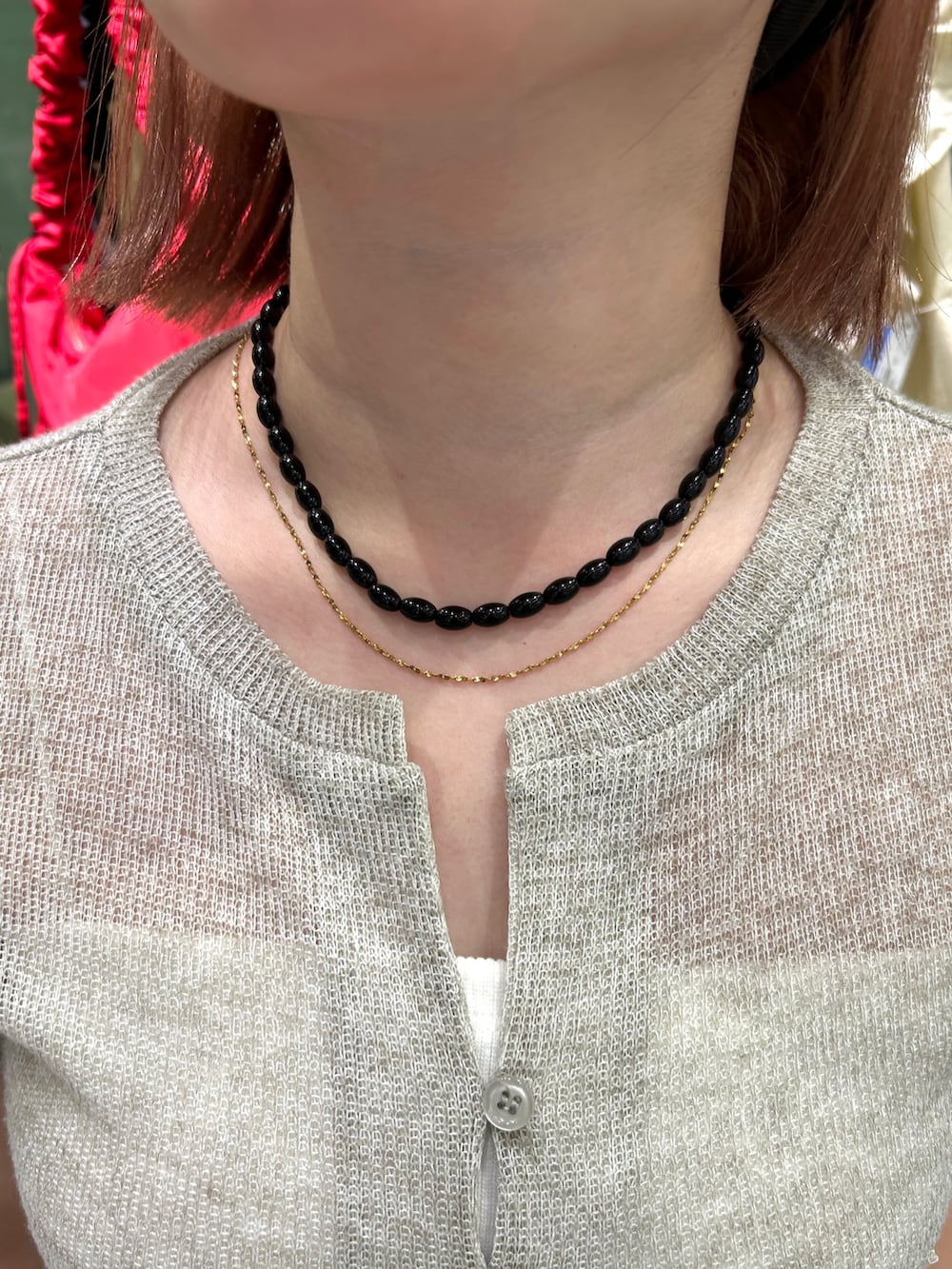 レッド系のショルダーバッグ、ブラック系のネックレス、ゴールド系のネックレスを着用したレディースの秋コーディネートの4枚目の写真