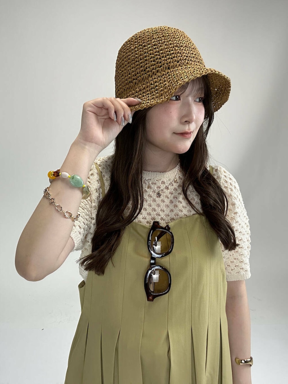 レッド系のハンドバッグ、ブルー系のデニムパンツ、ベージュ系のワンピースを着用したレディースの夏コーディネートの4枚目の写真