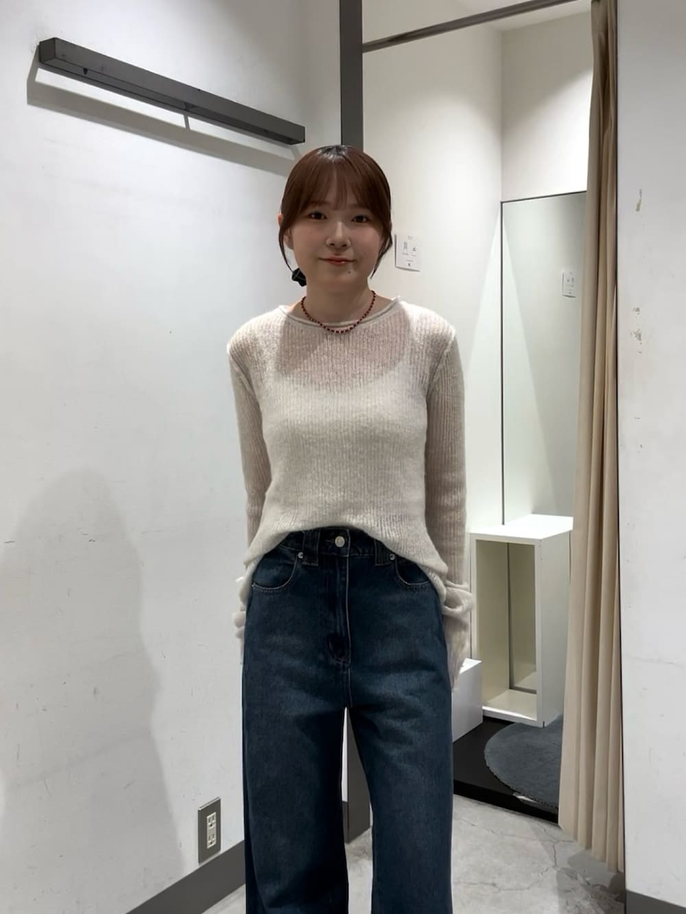 ホワイト系のニット/セーター、ホワイト系のキャミソール、ブルー系のデニムパンツを着用したレディースの秋コーディネートの3枚目の写真