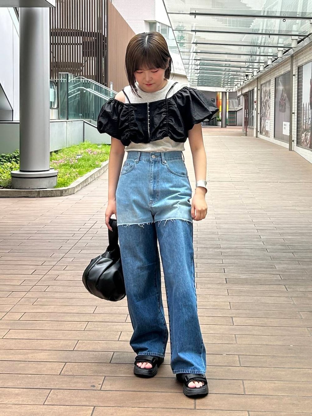 ブラック系のハンドバッグ、ブラック系のその他トップス、ブルー系のデニムパンツを着用したレディースの夏コーディネートの2枚目の写真