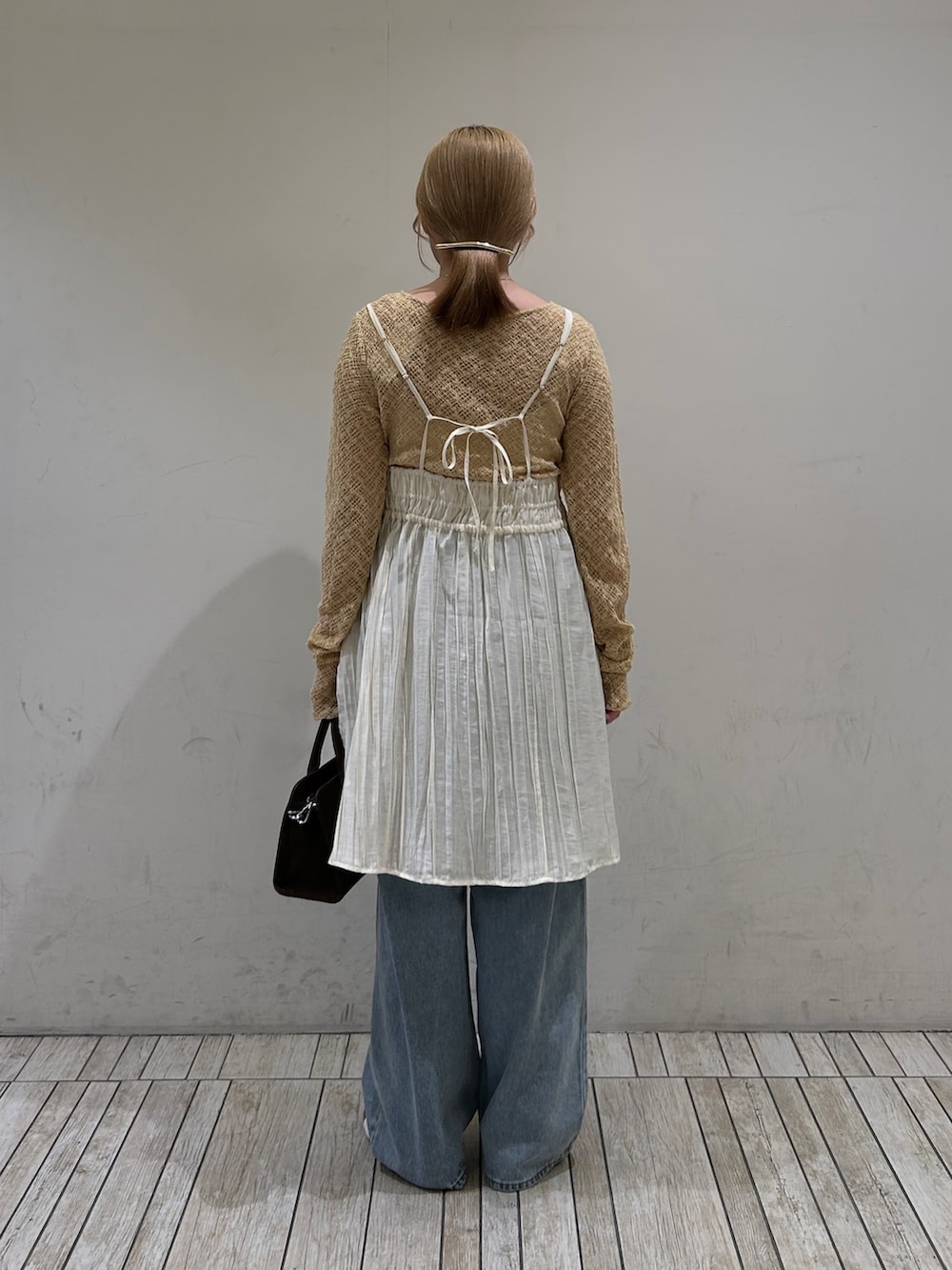 ブラウン系のスニーカー、ブルー系のデニムパンツ、ホワイト系のワンピースを着用したレディースの春コーディネートの3枚目の写真