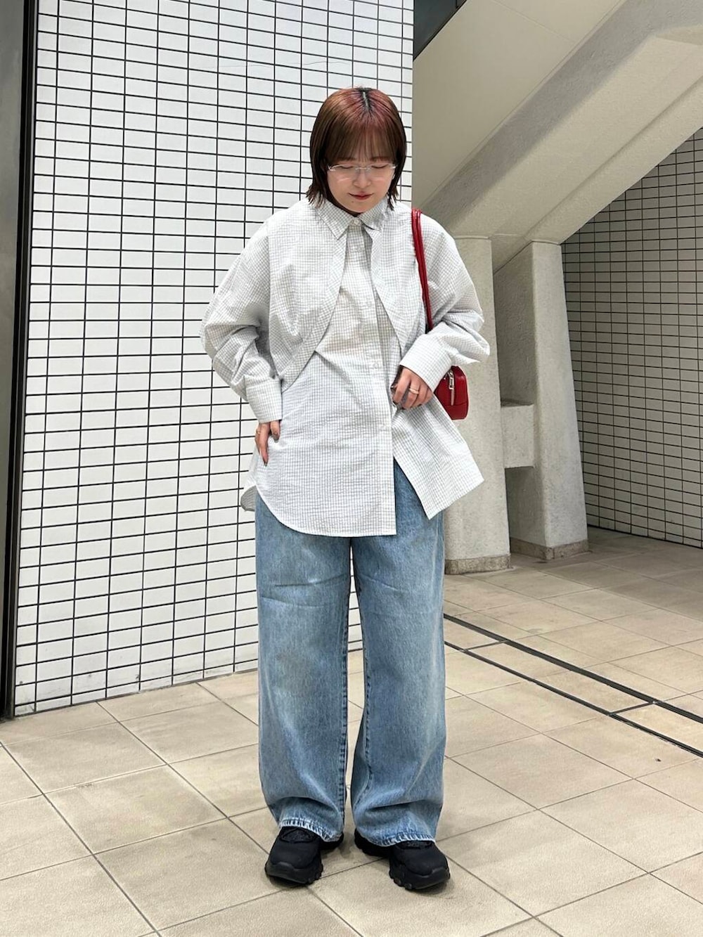 ブルー系のデニムパンツ、ブラック系のスニーカー、レッド系のショルダーバッグを着用したレディースの冬コーディネートの4枚目の写真