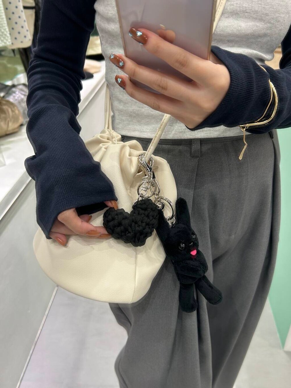 ホワイト系のショルダーバッグ、シルバー系のブレスレット、ブラック系のキーホルダーを着用したレディースの春コーディネートの2枚目の写真