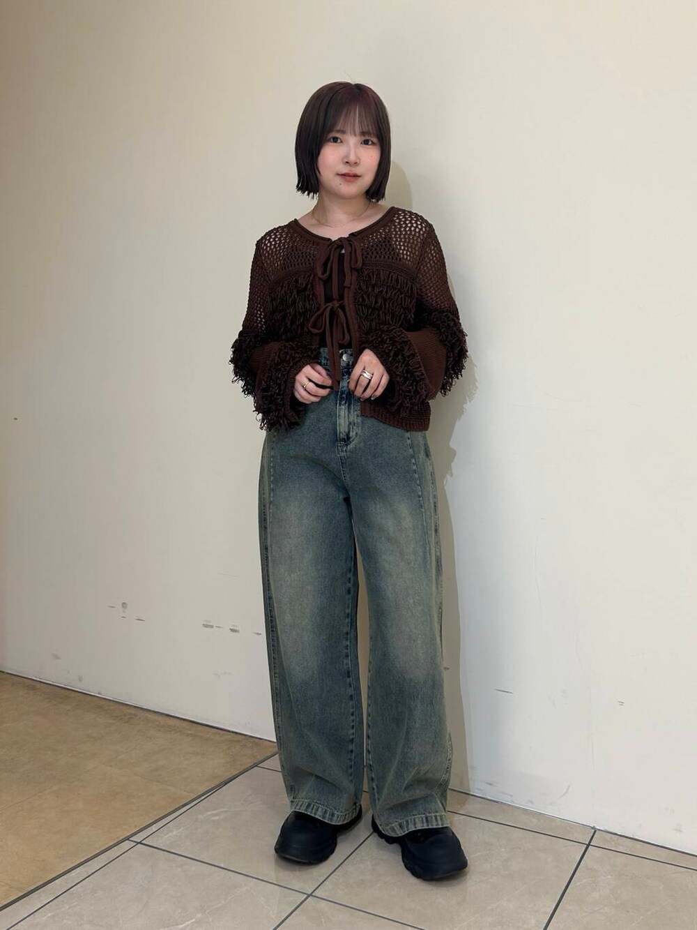 ブラック系のブーツ、ブルー系のデニムパンツ、ブラウン系のニット/セーターを着用したレディースの冬コーディネートの2枚目の写真