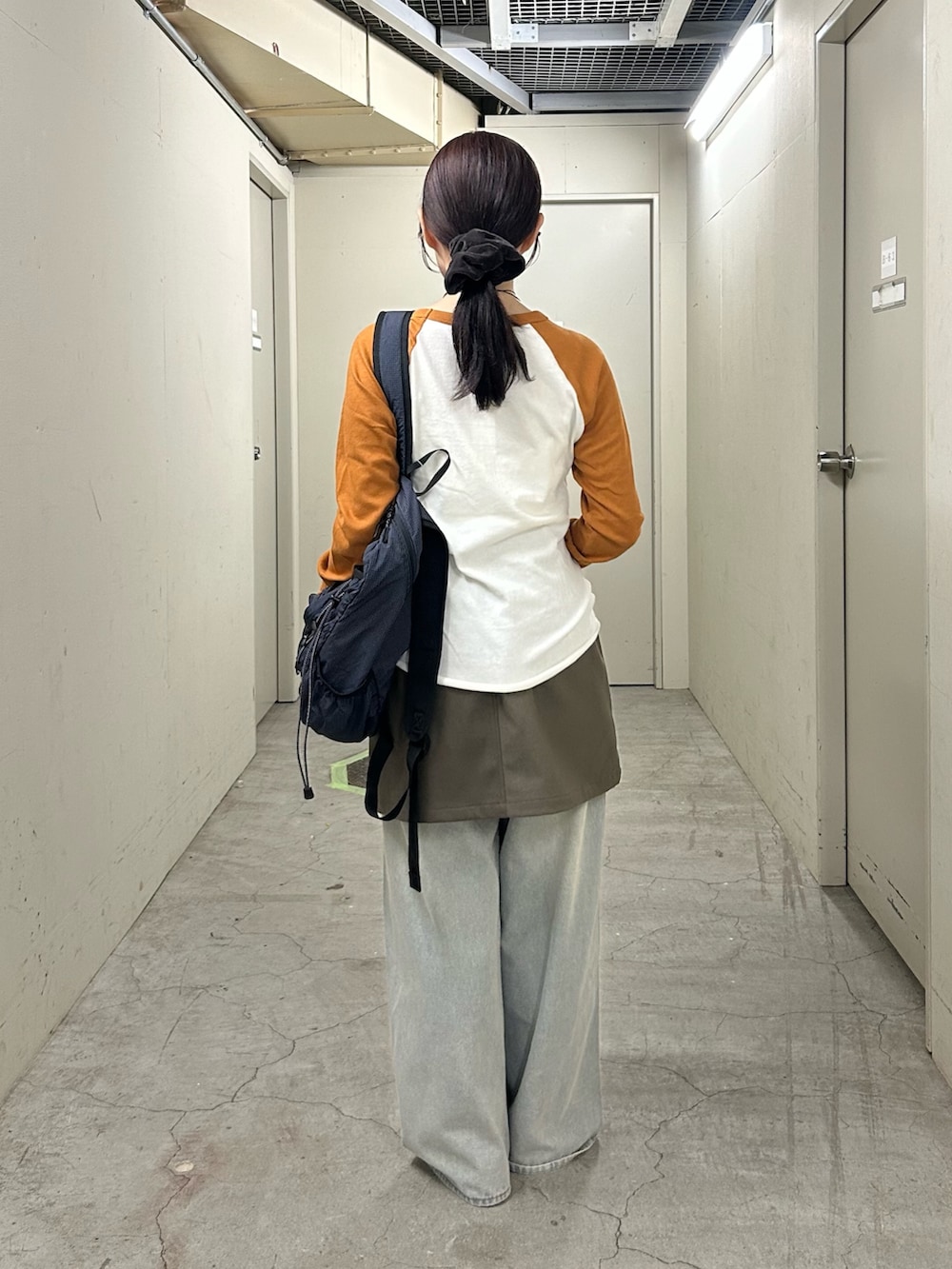 グリーン系のスカート、ブルー系のデニムパンツ、ブラウン系のローファーを着用したレディースの秋コーディネートの4枚目の写真