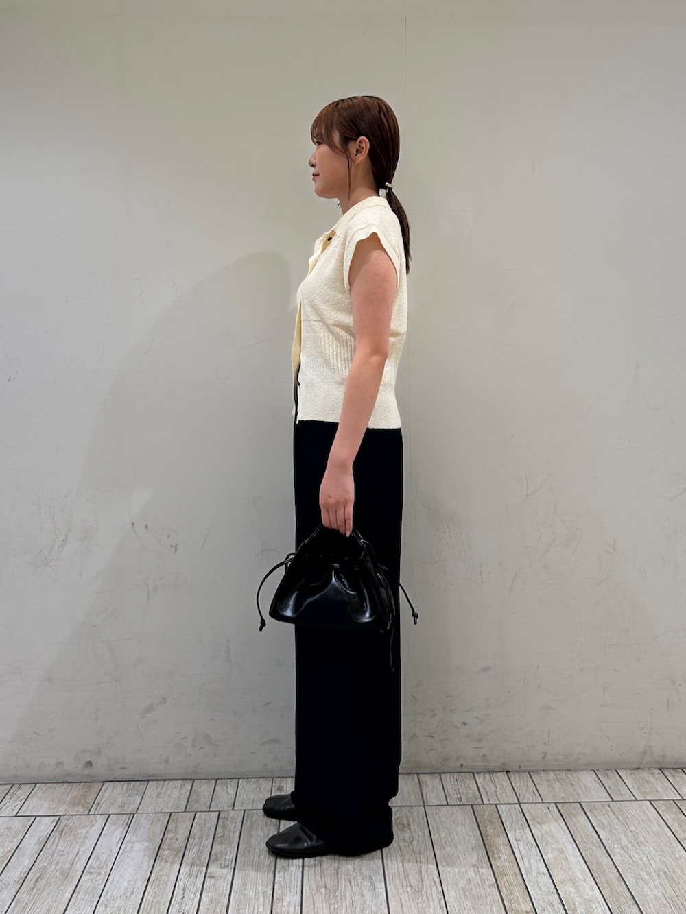 ホワイト系のニット/セーター、ブルー系のその他パンツ、ブラック系のハンドバッグを着用したレディースの夏コーディネートの3枚目の写真