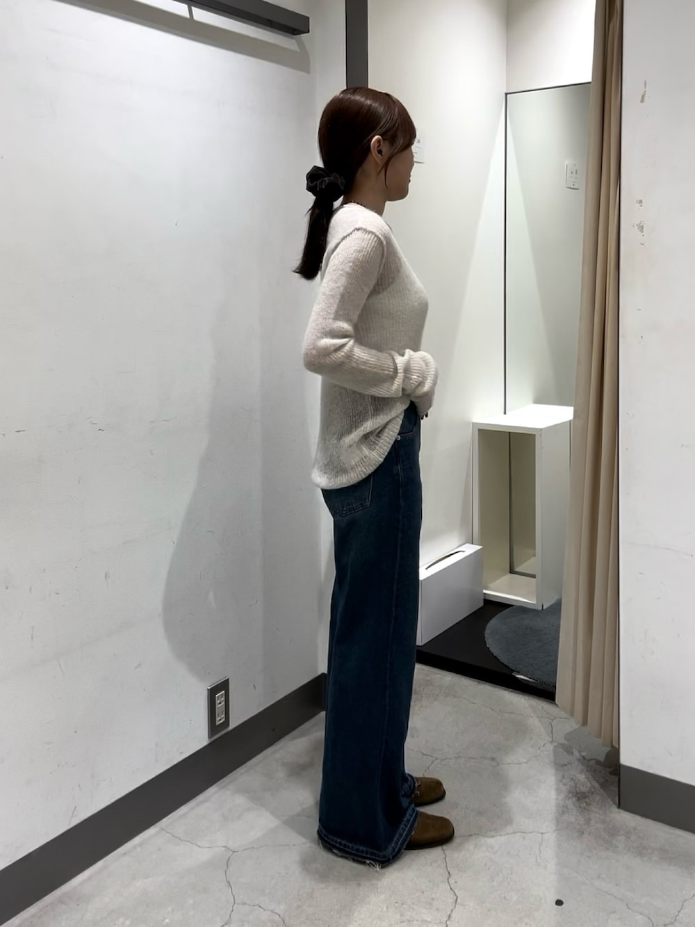 ホワイト系のニット/セーター、ホワイト系のキャミソール、ブルー系のデニムパンツを着用したレディースの秋コーディネートの2枚目の写真