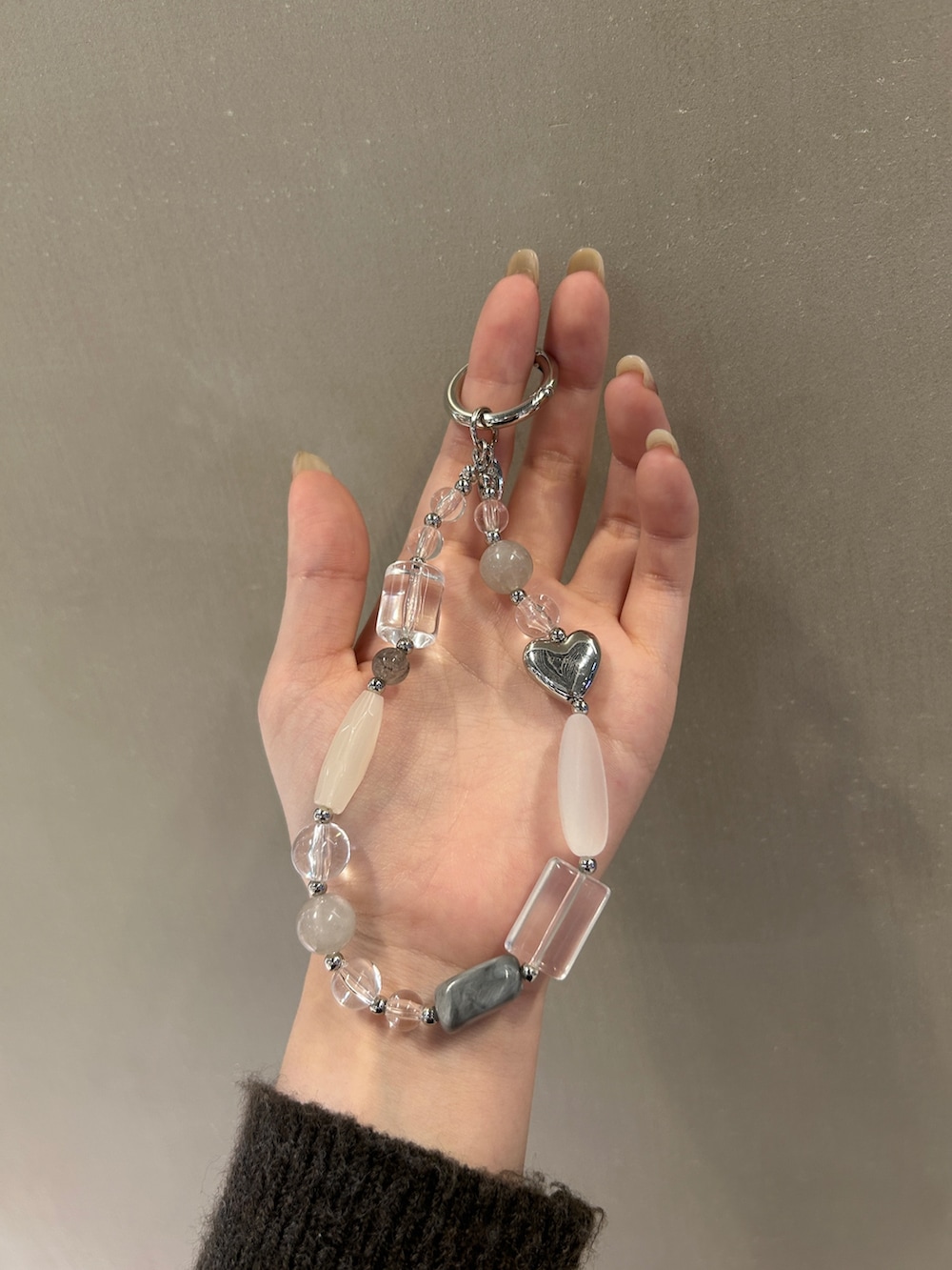 グレー系のトートバッグ、グレー系のキーホルダー、レッド系のネックレスを着用したレディースの冬コーディネートの4枚目の写真