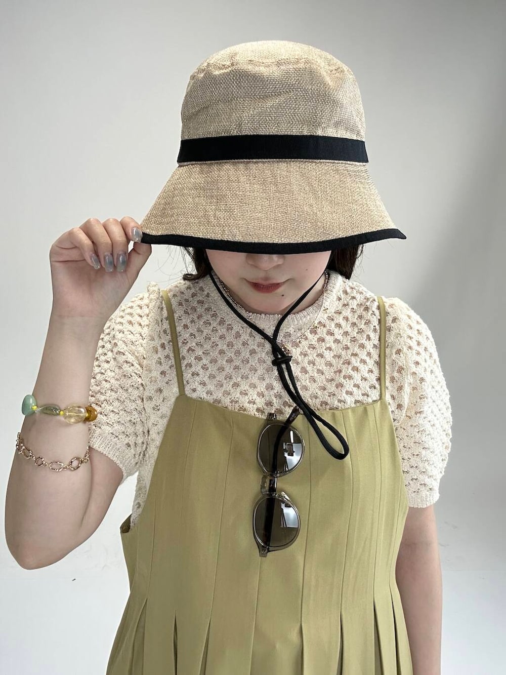 ホワイト系のニット/セーター、ベージュ系のワンピース、グレー系のメガネを着用したレディースの夏コーディネートの2枚目の写真