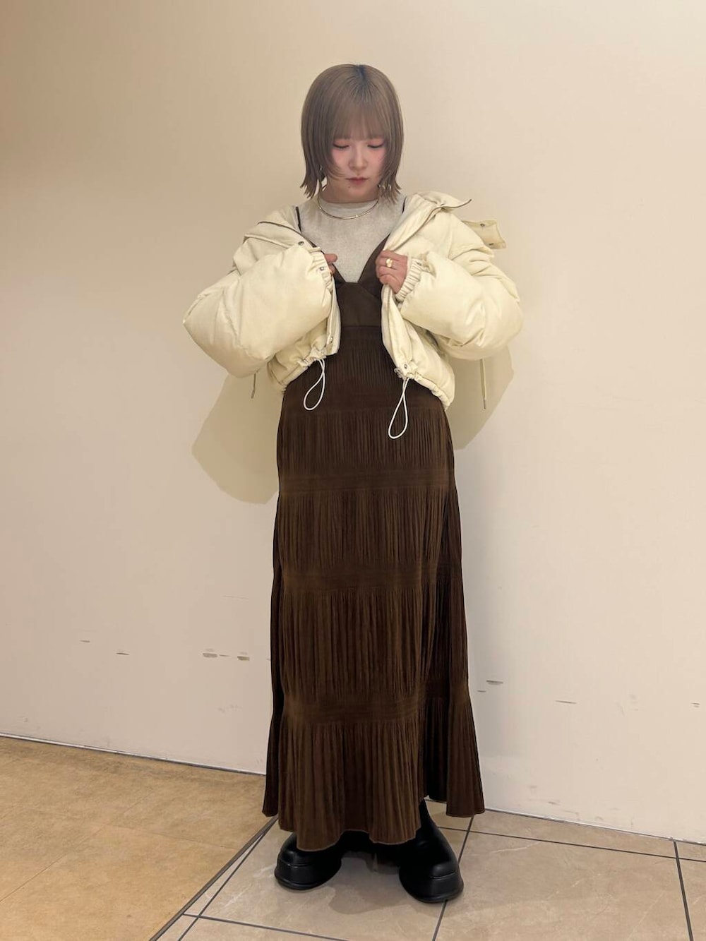 ホワイト系のダウンジャケット/コート、ブラウン系のワンピース、ホワイト系のニット/セーターを着用したレディースの冬コーディネートの2枚目の写真