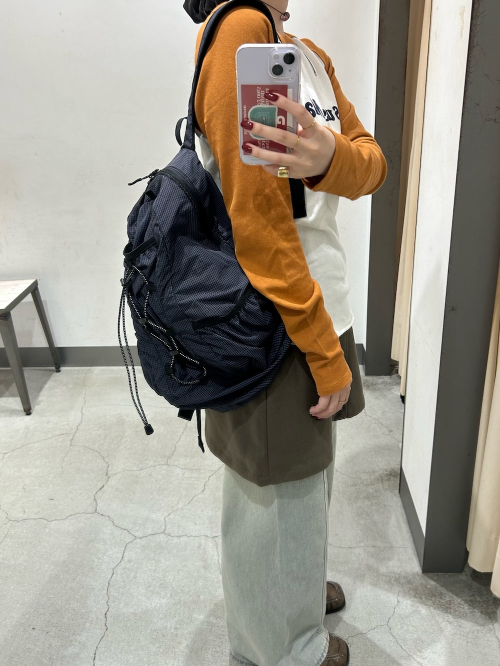 グリーン系のスカート、ブルー系のデニムパンツ、ブラウン系のローファーを着用したレディースの秋コーディネートの5枚目の写真