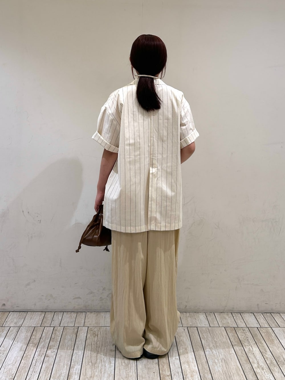 ホワイト系のその他アウター、イエロー系のその他パンツ、ブラウン系のハンドバッグを着用したレディースの夏コーディネートの3枚目の写真