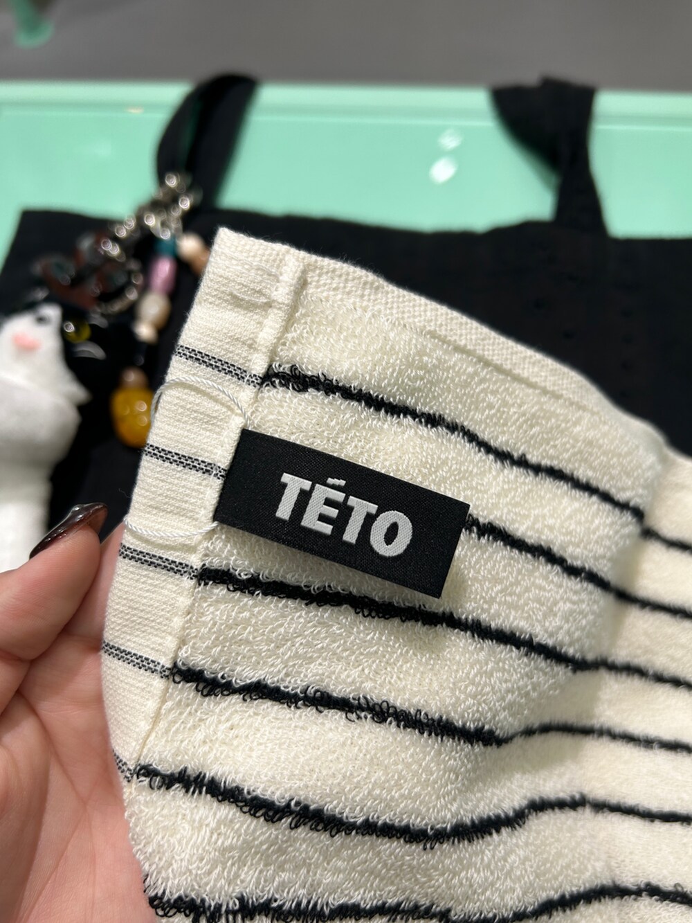 ブラック系のトートバッグ、ブラック系のキーホルダー、ブラック系のハンカチ/ハンドタオルを着用したレディースの秋コーディネートの3枚目の写真