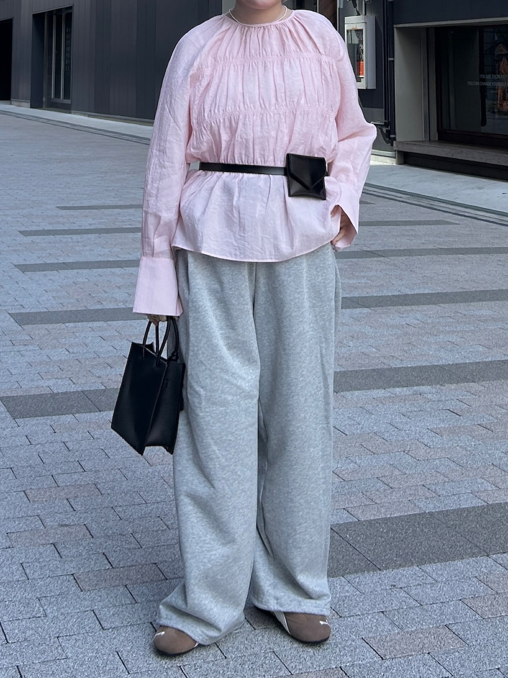 ピンク系のシャツ/ブラウス、グレー系のその他パンツ、ブラック系のハンドバッグを着用したレディースの春コーディネートの6枚目の写真