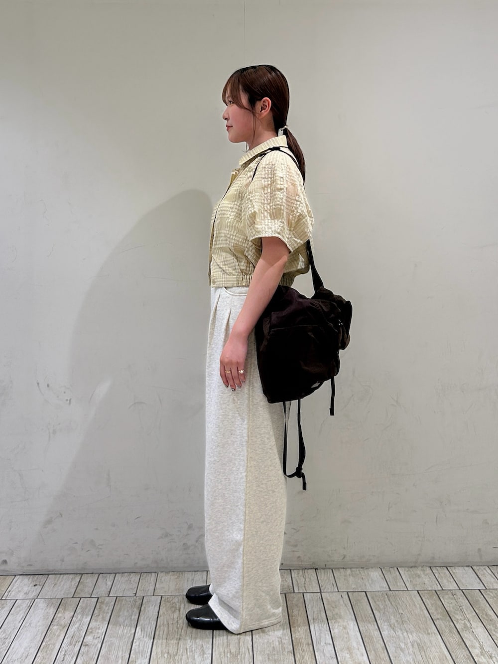 イエロー系のシャツ/ブラウス、ホワイト系のその他パンツ、ブラウン系のバックパック/リュックを着用したレディースの夏コーディネートの2枚目の写真