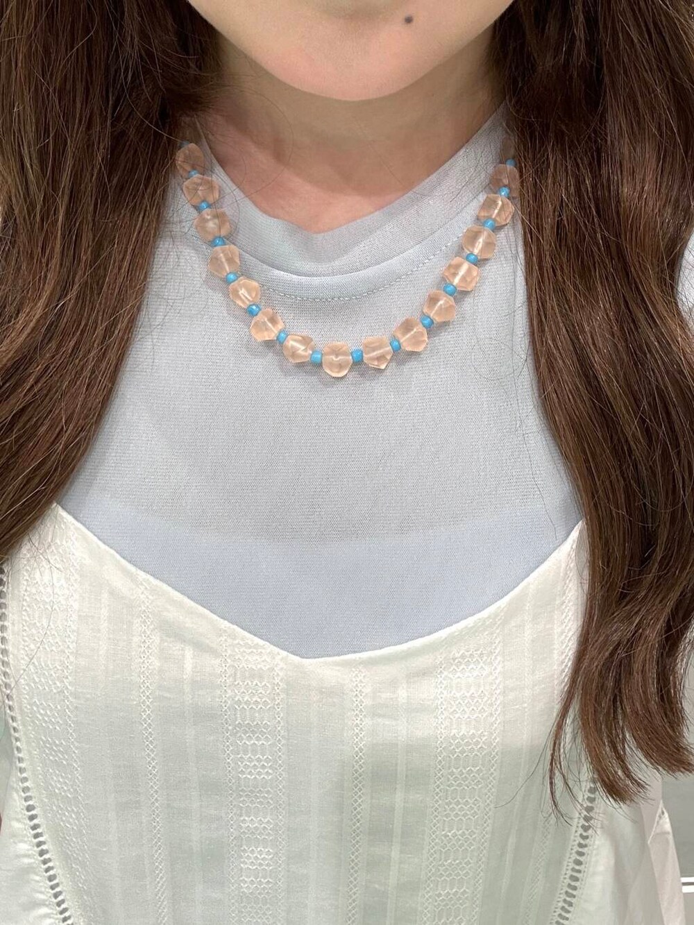 ピンク系のネックレス、シルバー系のスマホケース/カバーを着用したレディースの夏コーディネートの2枚目の写真