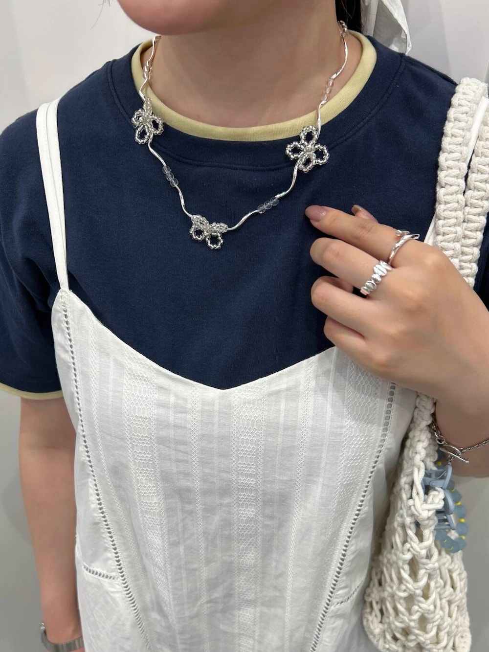 ホワイト系のハンドバッグ、シルバー系のリング、ホワイト系のバレッタ/ヘアクリップを着用したレディースの夏コーディネートの3枚目の写真
