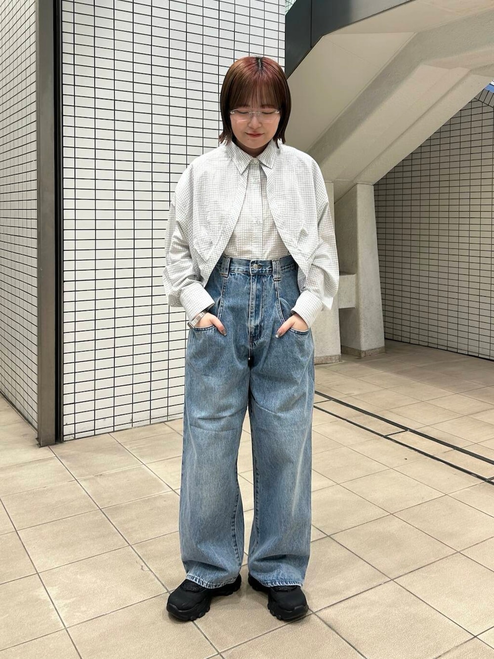 ブルー系のデニムパンツ、ブラック系のスニーカー、レッド系のショルダーバッグを着用したレディースの冬コーディネートの2枚目の写真