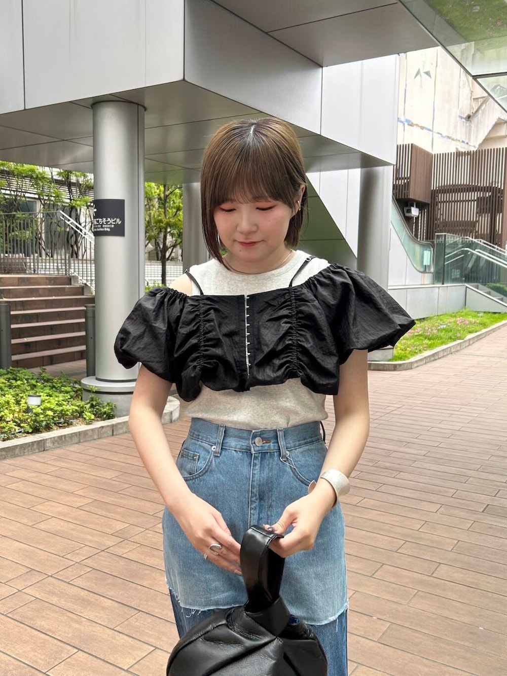 ブラック系のハンドバッグ、ブラック系のその他トップス、ブルー系のデニムパンツを着用したレディースの夏コーディネートの4枚目の写真