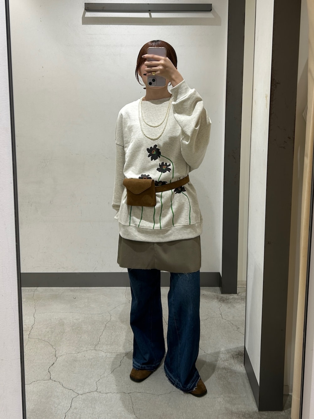 イエロー系のボディバッグ/ウエストポーチ、グレー系のスカート、ブルー系のデニムパンツを着用したレディースの秋コーディネートの2枚目の写真