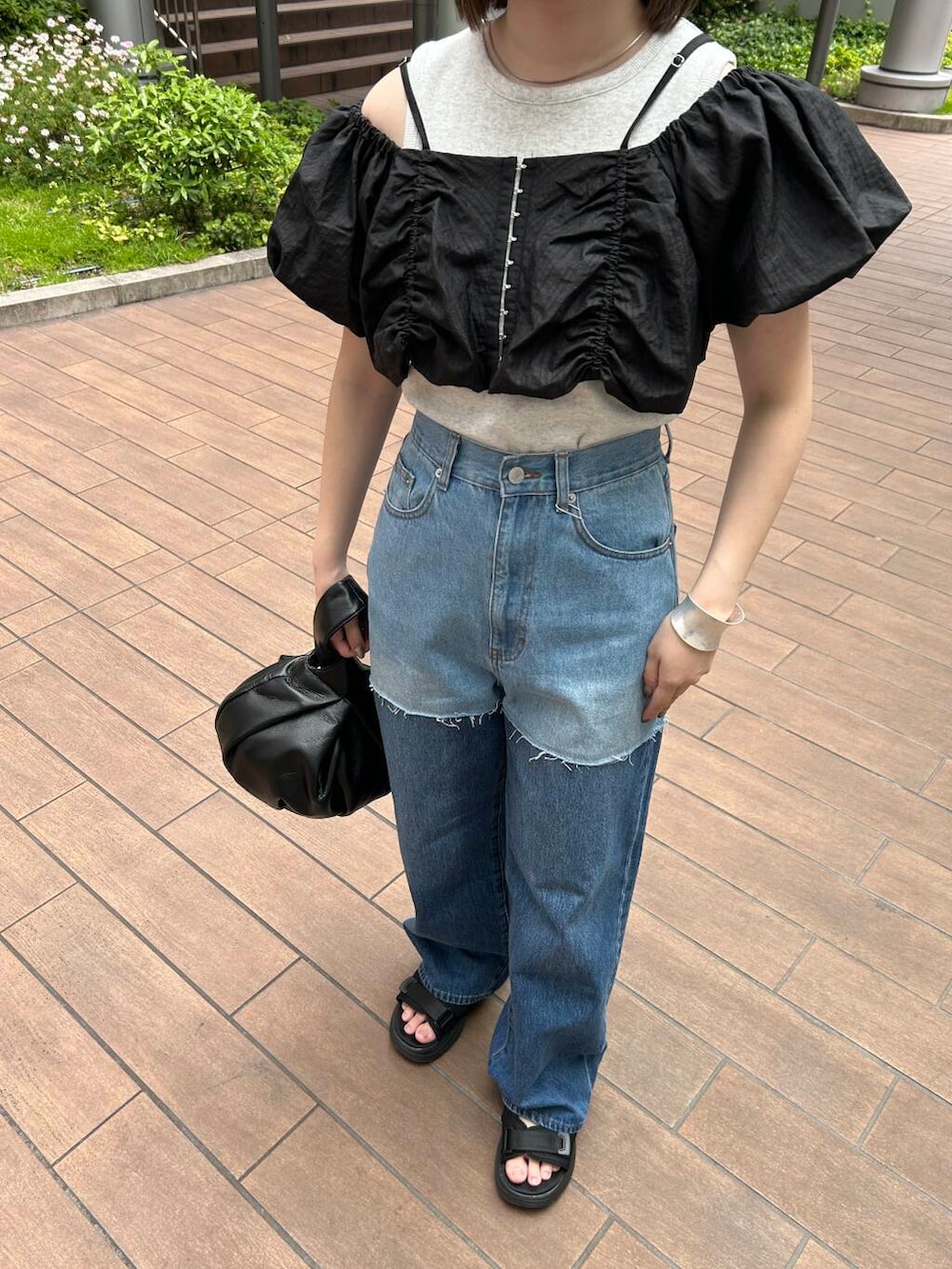 ブラック系のハンドバッグ、ブラック系のその他トップス、ブルー系のデニムパンツを着用したレディースの夏コーディネートの3枚目の写真