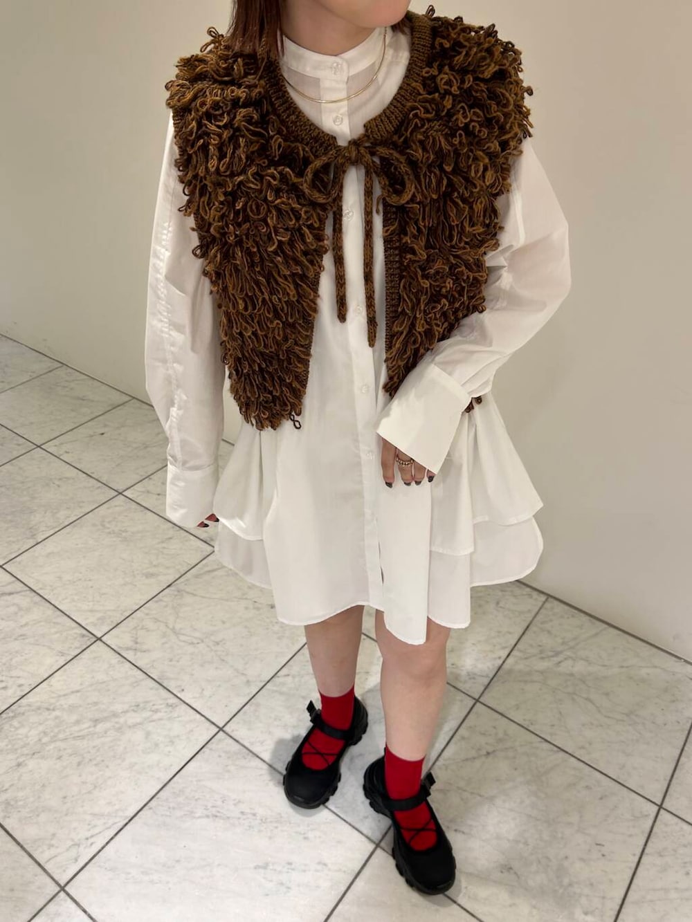 ブラック系のスニーカー、ブラウン系のベスト、ホワイト系のワンピースを着用したレディースの夏コーディネートの7枚目の写真