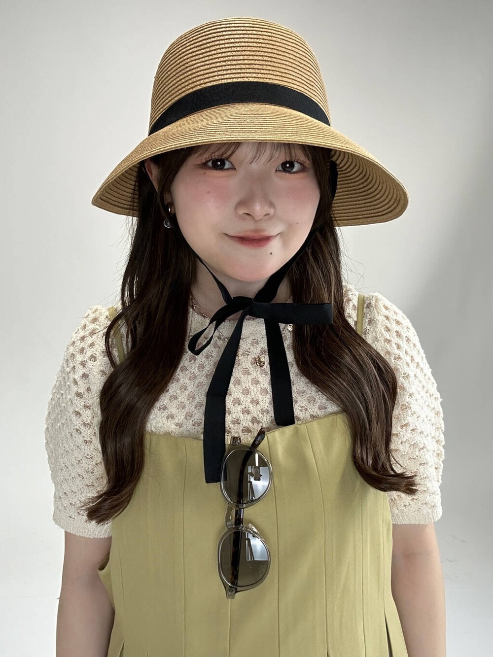 ホワイト系のニット/セーター、ベージュ系のワンピース、グレー系のメガネを着用したレディースの夏コーディネートの2枚目の写真