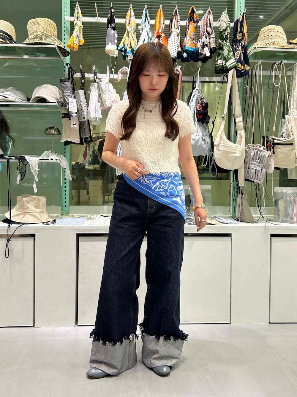 ブルー系のデニムパンツ、イエロー系のニット/セーター、シルバー系のネックレスを着用したレディースの春コーディネートの2枚目の写真