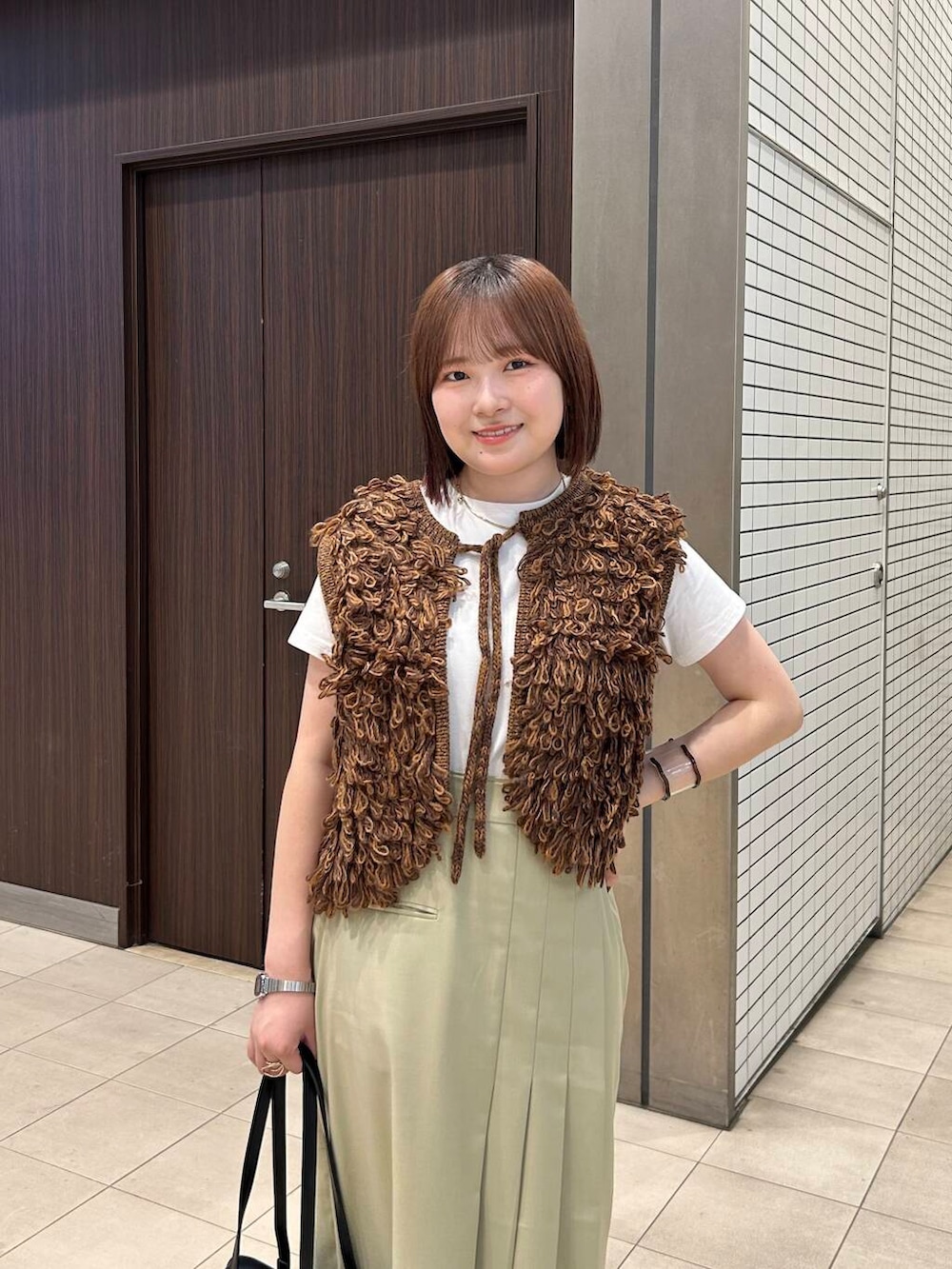 ホワイト系のTシャツ/カットソー、ブラウン系のベスト、ブラック系のボストンバッグを着用したレディースの夏コーディネートの8枚目の写真