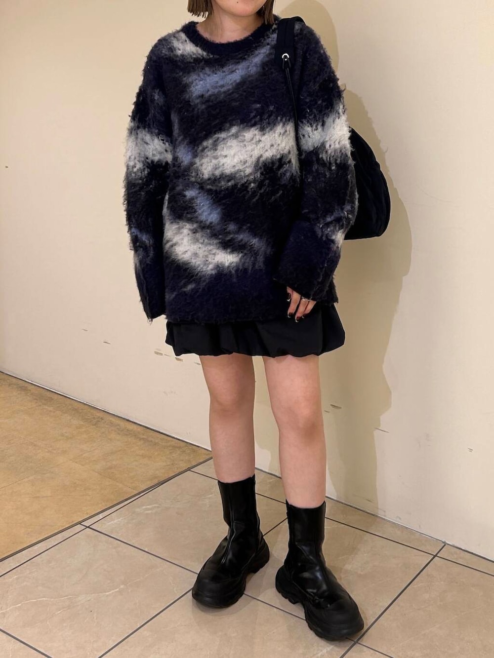 グレー系のスカート、ブラック系のブーツ、ブルー系のショルダーバッグを着用したレディースの秋コーディネートの3枚目の写真