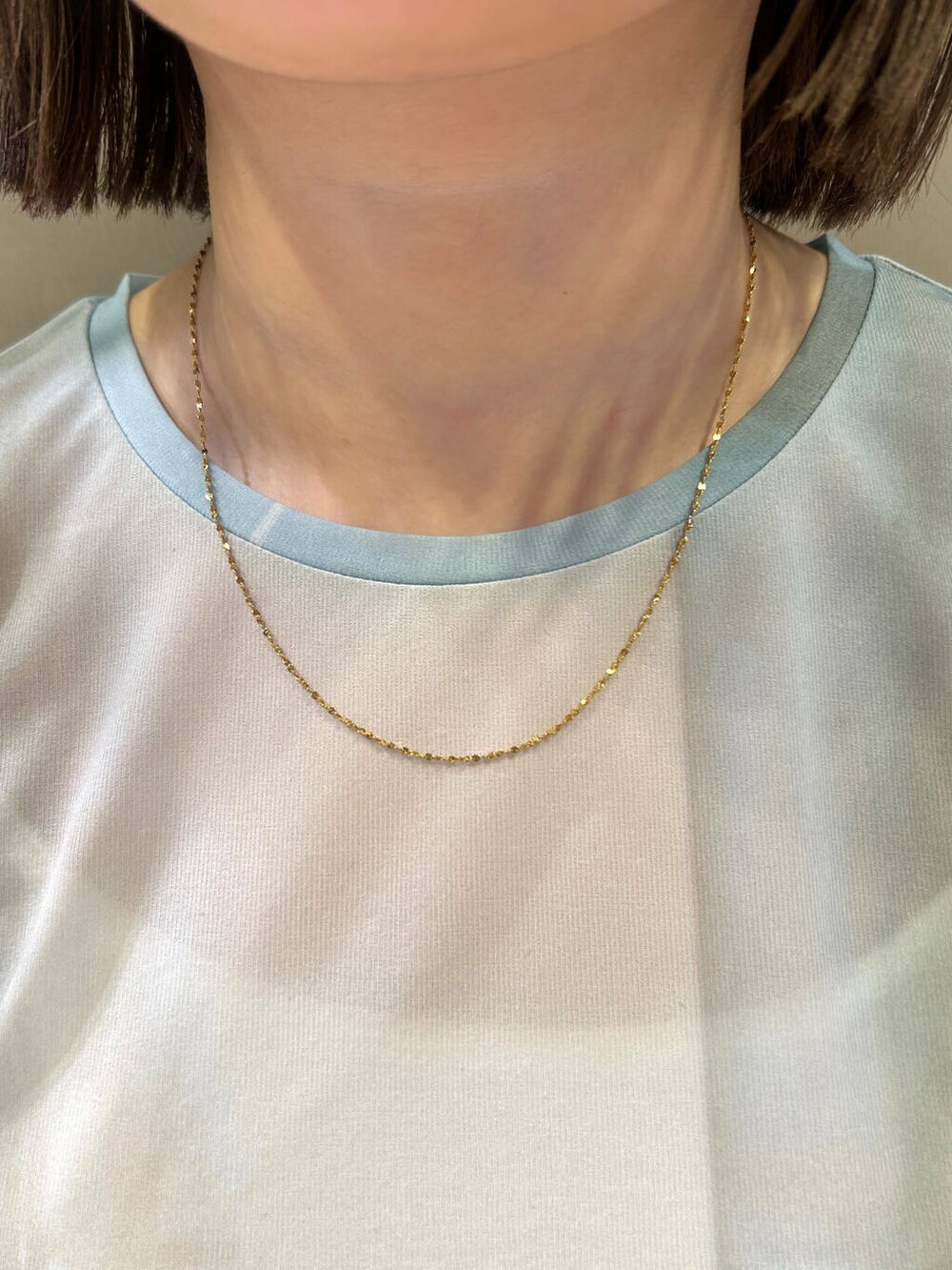 ゴールド系のネックレスを着用したレディースの春コーディネートの2枚目の写真
