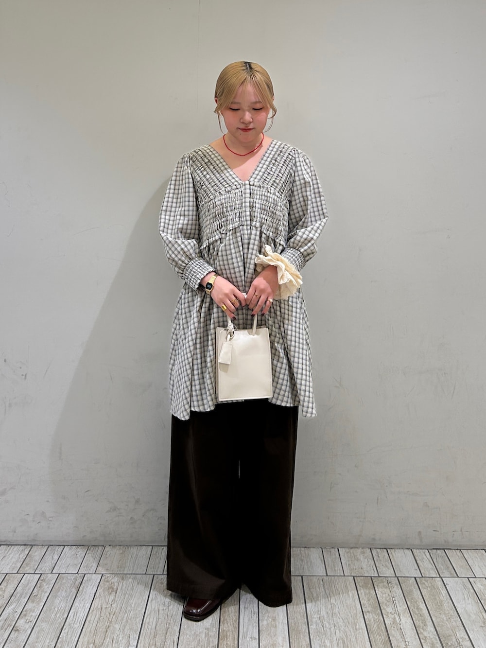 ベージュ系のワンピース、ホワイト系のハンドバッグ、ブラウン系のその他パンツを着用したレディースの春コーディネートの2枚目の写真