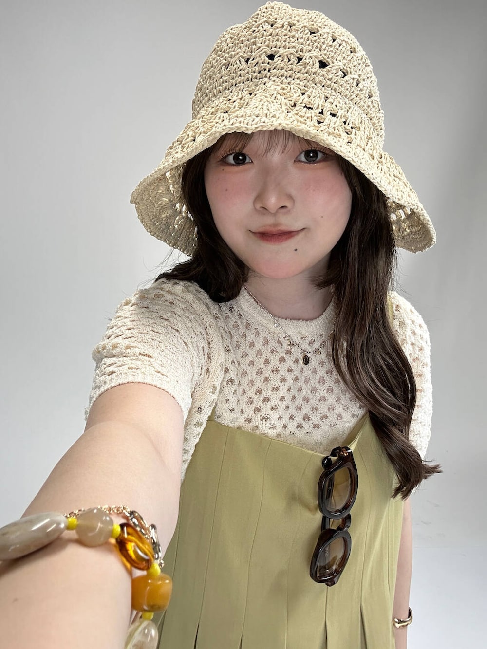 ホワイト系のニット/セーター、ベージュ系のワンピース、ブラウン系のメガネを着用したレディースの夏コーディネートの2枚目の写真