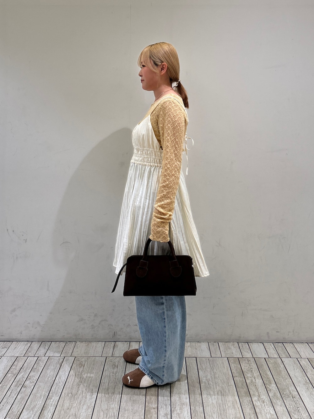 ブラウン系のスニーカー、ブルー系のデニムパンツ、ホワイト系のワンピースを着用したレディースの春コーディネートの2枚目の写真