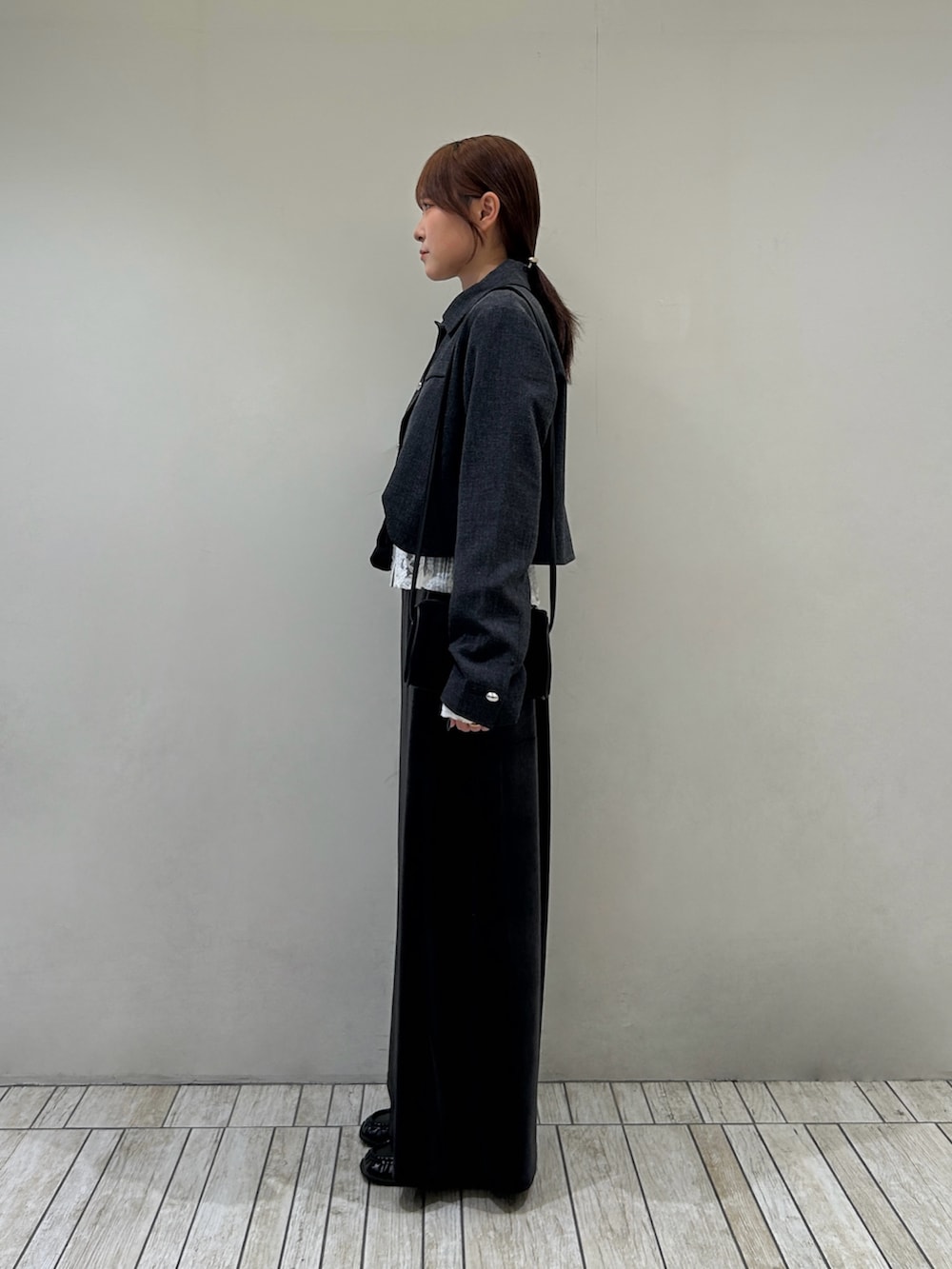 グレー系のブルゾン、ブラック系のローファー、ホワイト系のカーディガン/ボレロを着用したレディースの秋コーディネートの2枚目の写真