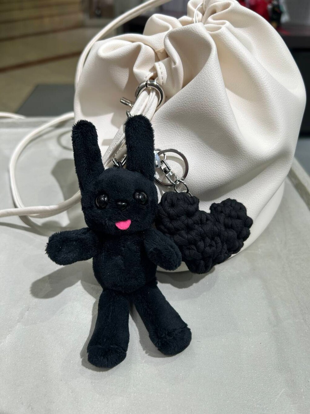 ホワイト系のショルダーバッグ、シルバー系のブレスレット、ブラック系のキーホルダーを着用したレディースの春コーディネートの3枚目の写真