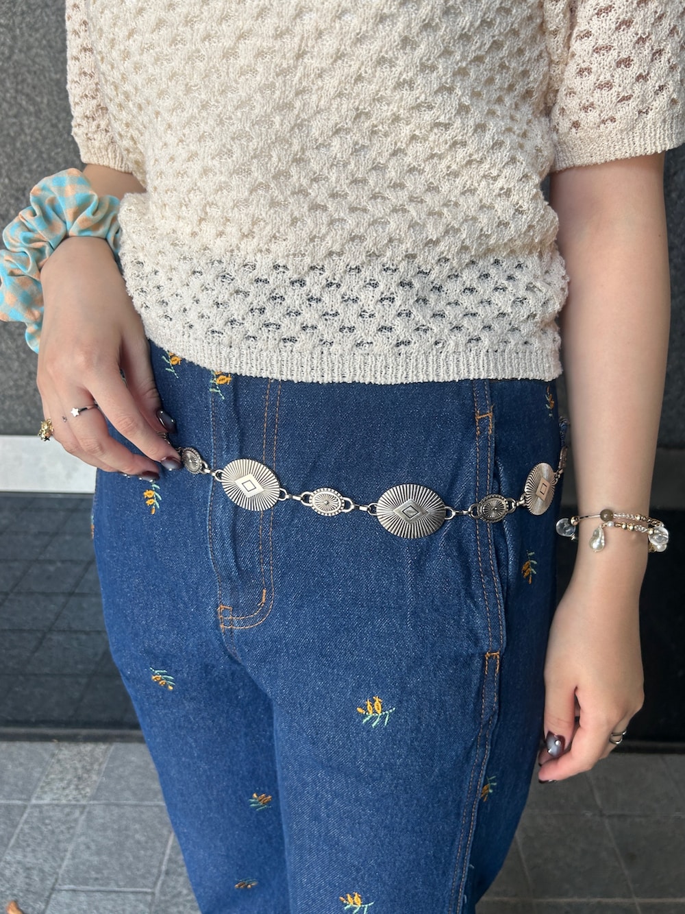 ホワイト系のニット/セーター、ブルー系のデニムパンツ、シルバー系のネックレスを着用したレディースの夏コーディネートの4枚目の写真